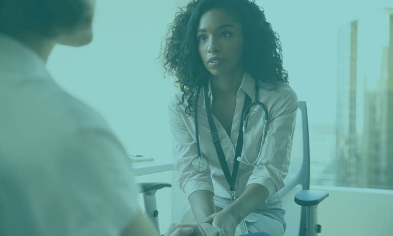 female doctor supporting female patient, image has a green overlay